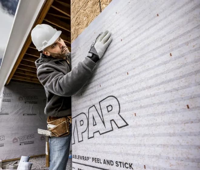 Construction worker installs weather smart wrap to home