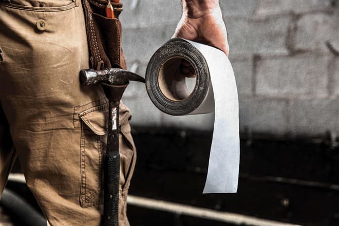 Man holding cold weather flashing tape roll on a jobsite